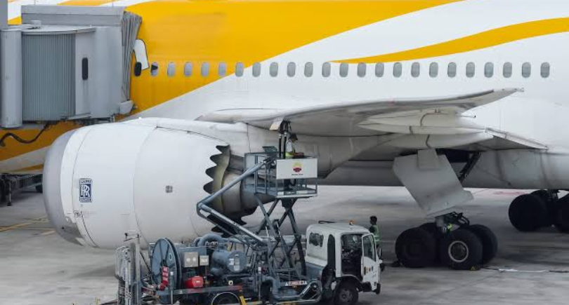 Aircraft engine maintenance equipment positioned beneath a parked airliner.