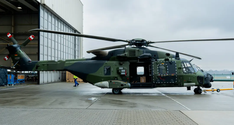 NH90 military helicopter parked outside an EFW maintenance hangar.