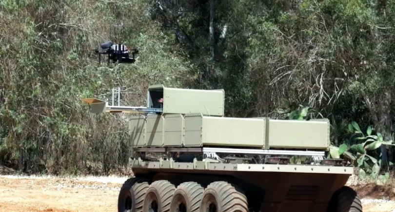 Autonomous ground vehicle with drone operating in wooded terrain.